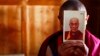 FILE - A monk holds a picture of Tibetan spiritual leader Dalai Lama inside of his room at Labrang Monastery in Xiahe county, Gansu Province.