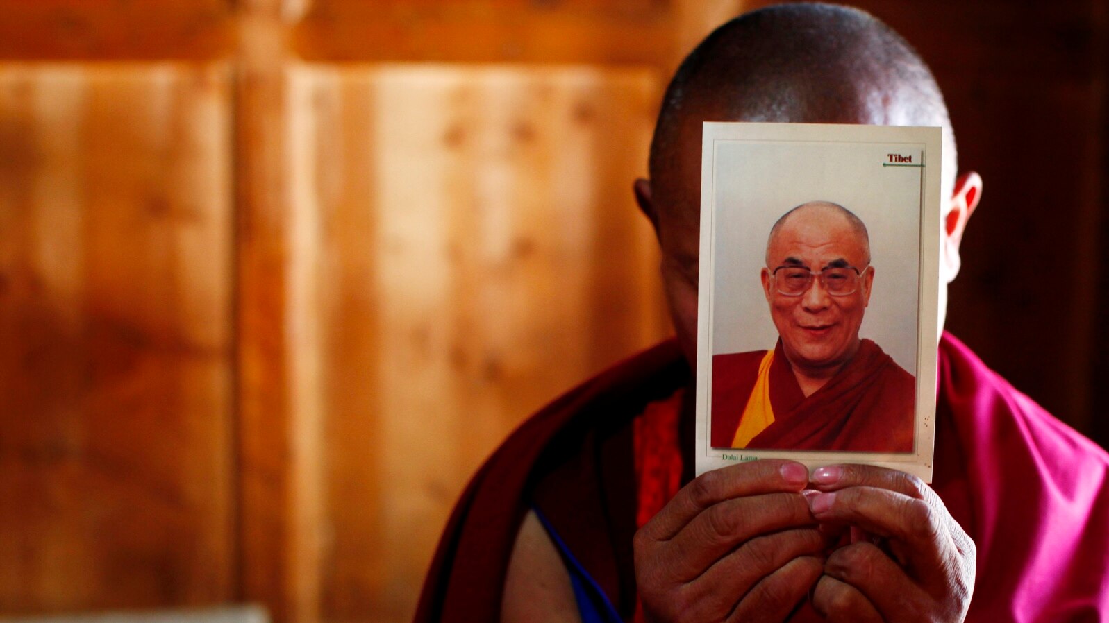 FILE - A monk is seen holding a picture of Tibetan spiritual leader Dalai Lama.