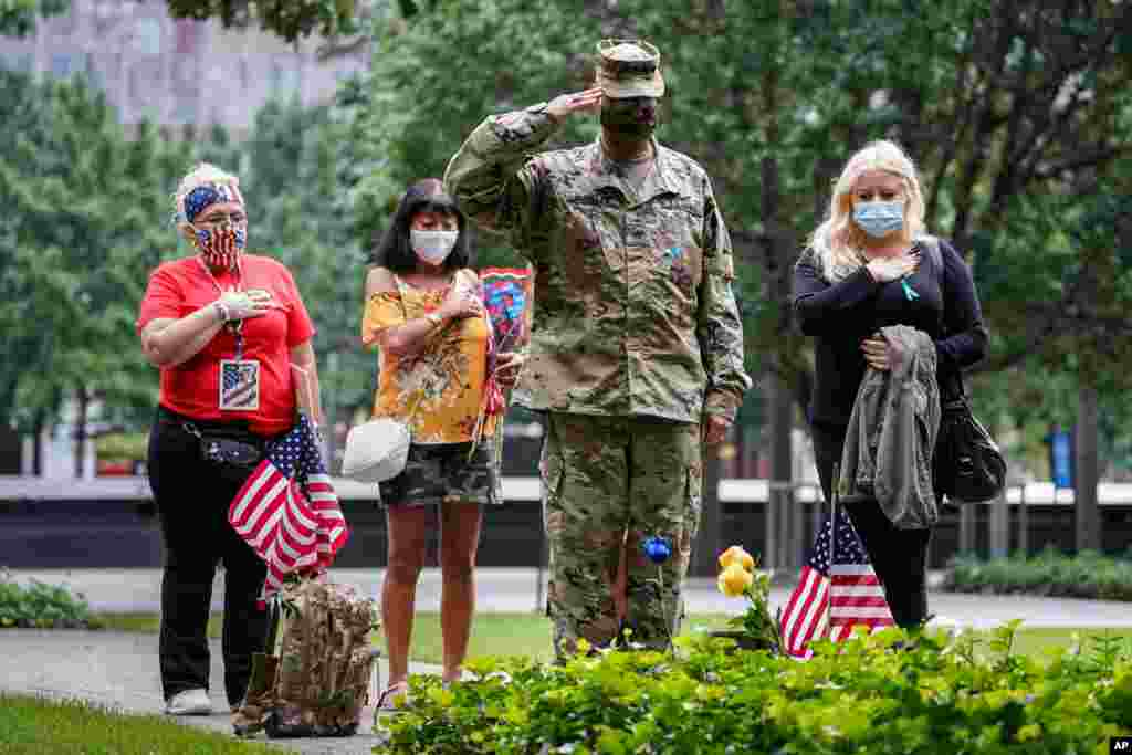 U.S. Army Sgt. Edwin Morales, center right, salutes after placing flowers for fallen FDNY firefighter Ruben D. Correa at the National September 11 Memorial and Museum in New York.