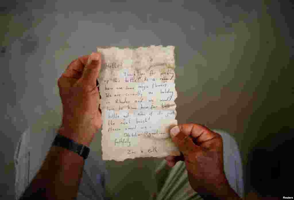 Palestinian fisherman Jihad al-Soltan displays a message that was written by Bethany Wright and her boyfriend Zac Marriner, after he found it in a bottle off a Gaza beach, Aug. 21, 2017.