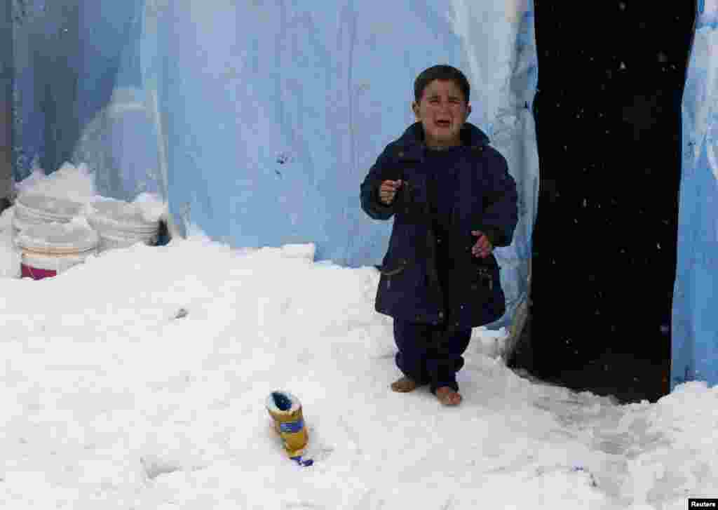 A Syrian refugee boy reacts as he stands barefoot on snow outside a tent at a refugee camp in Zahle, in the Bekaa valley, Lebanon. A storm buffeted the Middle East with blizzards, rain and strong winds, keeping people at home across much of the region and raising concerns for Syrian refugees facing freezing temperatures in flimsy shelters.