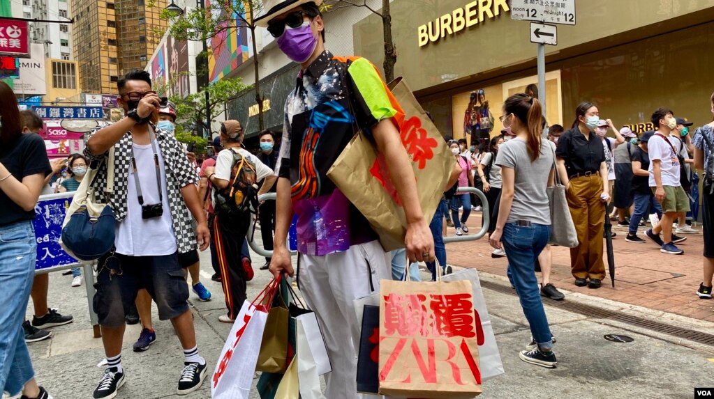 香港异见艺术家黄国才2020年7月1日，香港国安法实施第一日，在铜锣湾以”血拼”为名，打扮成来自中国大陆的”豪客”，手持多个写上国安法相关罪名的百货公司购物袋，表现对实施国安法的不安 （美国之音/汤惠芸）(photo:VOA)