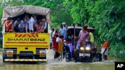 FILE - Flood-affected people are rescued in a tractor, right, as volunteers go for rescue work in a truck, left, at Kainakary in Alappuzha district, Kerala state, India, Aug. 17, 2018.
