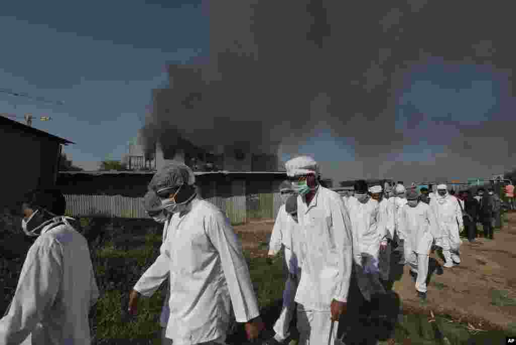 Employees leave as smoke rises from a fire at Serum Institute of India, the world&#39;s largest vaccine maker that is manufacturing the AstraZeneca/Oxford University vaccine for the coronavirus, in Pune, India.