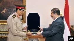 FILE - Former Defense Minister Hussein Tantawi, left, receives a high medal from Egyptian President Mohammed Morsi at the Presidential Palace in Cairo, Egypt, Aug. 14, 2012.
