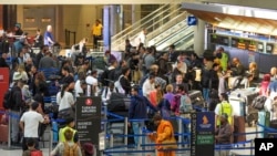 Pasajeros internacionales hacen fila para registrarse para viajar en el Aeropuerto Internacional de Los Ángeles, en Los Ángeles, el miércoles 27 de noviembre de 2024. (Foto AP/Damian Dovarganes).