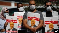 FILE - People hold posters of slain Saudi journalist Jamal Khashoggi, near the Saudi consulate in Istanbul, Turkey, marking the second anniversary of his death, Oct. 2, 2020.