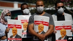 People hold posters of slain Saudi journalist Jamal Khashoggi, near the Saudi Arabia consulate in Istanbul, marking the two-year anniversary of his death, Oct. 2, 2020.