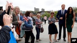 Tourists gather to take photos with waxwork figures of Britain's Prince Harry and Meghan Markle against the backdrop of Windsor Castle, in Windsor, England, May 16, 2018. 