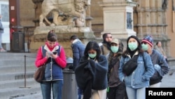 Para pengunjung mengenakan masker pelindung saat berjalan di Florence di tengah upaya pemerintah Italia memerangi wabah virus corona, Sabtu, 7 Maret 2020. 