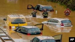 জার্মানির এরফস্তাডে বন্যার পানিতে রাস্তায় গাড়ী নিয়ে আটকে পড়া লোকজনদের সাহায্য করছেন উদ্ধারকর্মীরা। জুলাই ১৭, ২০২১। - এপি 