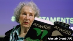 FILE - In this Sept. 10, 2019, file photo, Canadian author Margaret Atwood holds a copy of her book "The Testaments," during a news conference in London. (AP Photo/Alastair Grant, File)