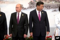 Russian President Vladimir Putin, left, and Chinese President Xi Jinping line up for a photo during the BRICS Summit in southeastern China's Fujian province, Sept. 4, 2017.