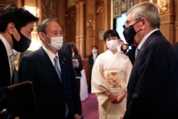 IOC President Thomas Bach, right, meets with Japanese Prime Minister Yoshihide Suga, second from left, during a welcome party for Bach and IOC officials at Akasaka Palace, Japanese state guest house, in Tokyo, Japan, Sunday, July 18, 2021.