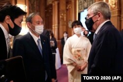 IOC President Thomas Bach, right, meets with Japanese Prime Minister Yoshihide Suga, second from left, during a welcome party for Bach and IOC officials at Akasaka Palace, Japanese state guest house, in Tokyo, Japan, Sunday, July 18, 2021.