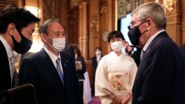 IOC President Thomas Bach, right, meets with Japanese Prime Minister Yoshihide Suga, second from left, during a welcome party for Bach and IOC officials at Akasaka Palace, Japanese state guest house, in Tokyo, Japan, Sunday, July 18, 2021.