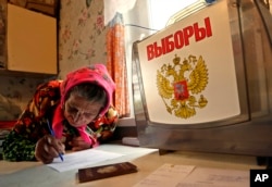 FILE - A woman fills her ballot while being visited by a mobile election committee, who visit those people that are not able to walk to polling stations, in the village of Zebrevitsa, outside Smolensk, western Russia, Sept. 18, 2016.