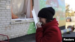 FILE - A woman cries outside a local kindergarten, which was damaged by explosions at a military depot in Svatove, Luhansk region, Ukraine, Oct. 30, 2015.