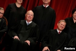 FILE - U.S. Supreme Court Justice Anthony Kennedy (L) reacts while chatting with Chief Justice John Roberts (R) during a new U.S. Supreme Court family photo.