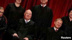 FILE - U.S. Supreme Court Justice Anthony Kennedy (L) reacts while chatting with Chief Justice John Roberts (R) during a photo session with fellow justices at the Supreme Court building in Washington, June 1, 2017. 