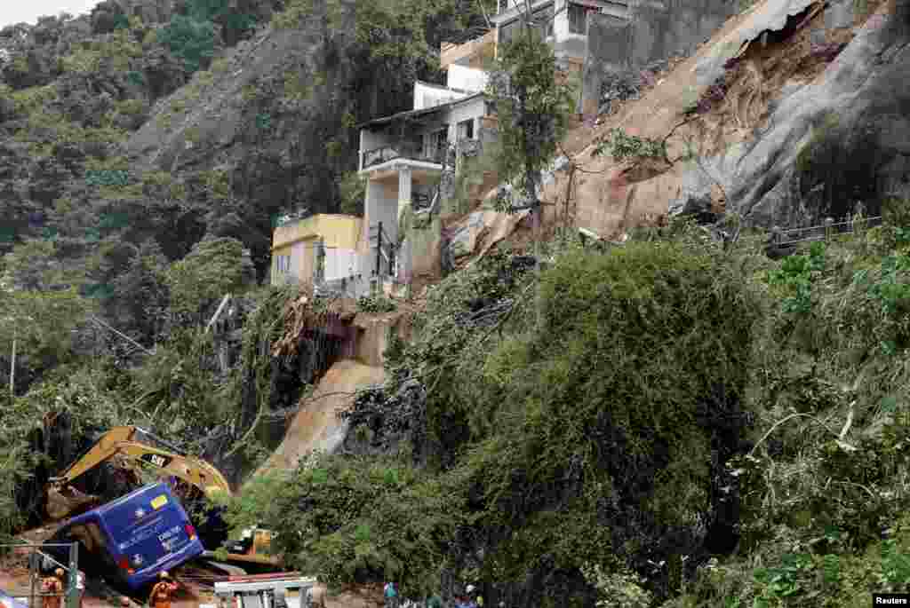 Firefighters search for victims inside a damaged bus, which was hit by a mudslide after heavy rains in Rio de Janeiro, Brazil.