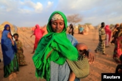 FILE - An internally displaced woman from drought hit area reacts after she complains about the lack of food at makeshift settlement area in Dollow, Somalia.