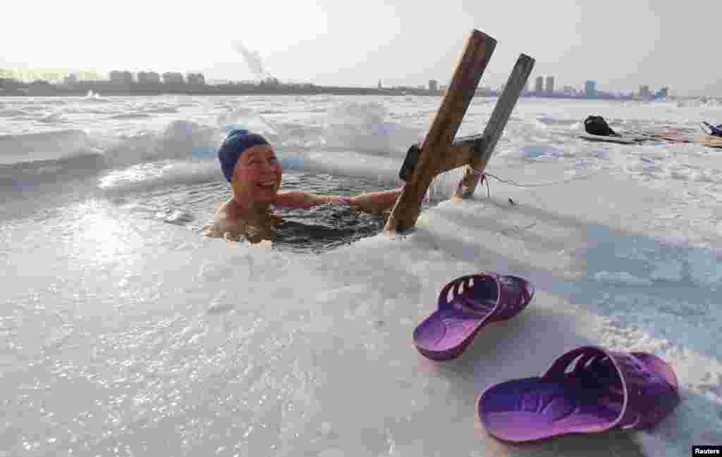 A woman takes a dip in icy water, with the buildings of Chinese border city Heihe seen in the background across the frozen Amur River, in Blagoveshchensk, in Amur region, Russia.