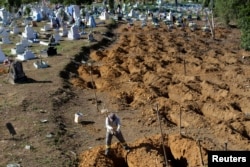 FILE - A man digs graves at the Parque Taruma cemetery in Manaus, Brazil, for inmates killed in a prison riot, Jan. 4, 2017.