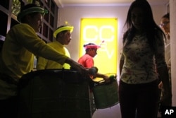 FILE - Henry Cubias, center, loads the drums that will be used together with his fellow artists in an anniversary celebration at the Spanish Embassy Cultural Center in San Salvador, El Salvador, June 29, 2018. In January, police stopped Cubias as he cycled home one night from his job. The police, some wearing hoods, took Cubias to a darkened area, jerked his head back by grabbing his long hair and told him they could make him disappear if he didn't inform on gang activities.