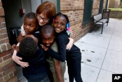 Charlie Branda, founder of Art on Sedgwick, hugs a few young residents of Marshall Field Garden Apartments in Chicago, June 25, 2018.