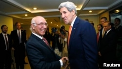 ລັດຖະມົນຕີຕ່າງປະເທດ ສະຫະລັດ ທ່ານ John Kerry ສຳພັດມືກັບ ທ່ານ Sartaj Aziz (ຊ້າຍ) ທີ່ປຶກສາດ້ານຄວາມປອດໄພແຫ່ງຊາດປາກິສຖານ. 