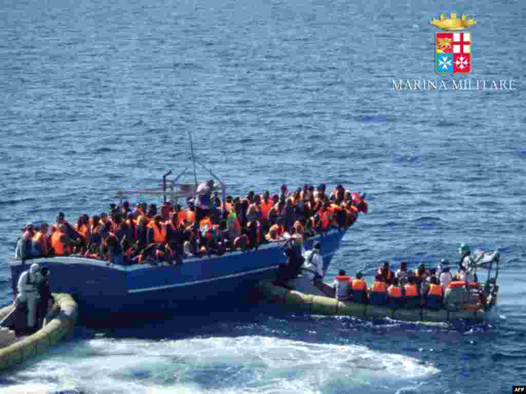 In this handout picture released by the Italian navy, migrants sit on a overcrowded boat during a rescue operation off the coast of Sicily. Around 1,000 migrants has been rescued in the last 24 hours by ships engaged in the &quot; Mare Nostrum&quot; operation.