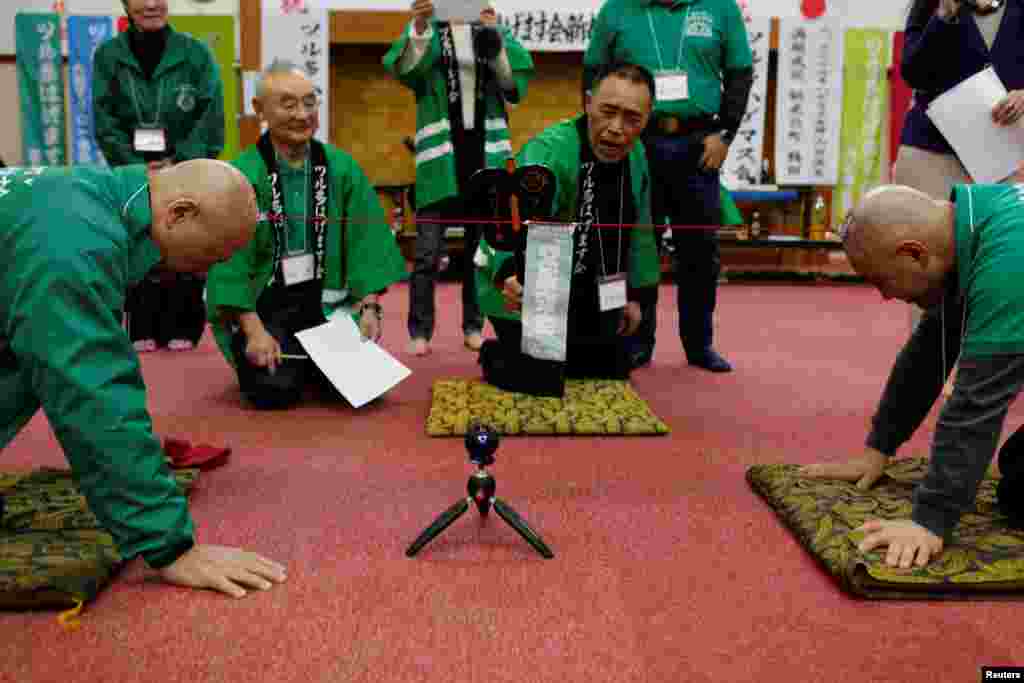 Members of the Bald Men Club take part in a unique game of tug-of-war by attaching suction pads onto their heads, at a hot spring facility in Tsuruta town, Aomori prefecture, Japan.