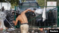 Migrants react on the Serbian side of the border as Hungarian riot police fires tear gas and water cannon near Roszke, Hungary, Sept. 16, 2015. 