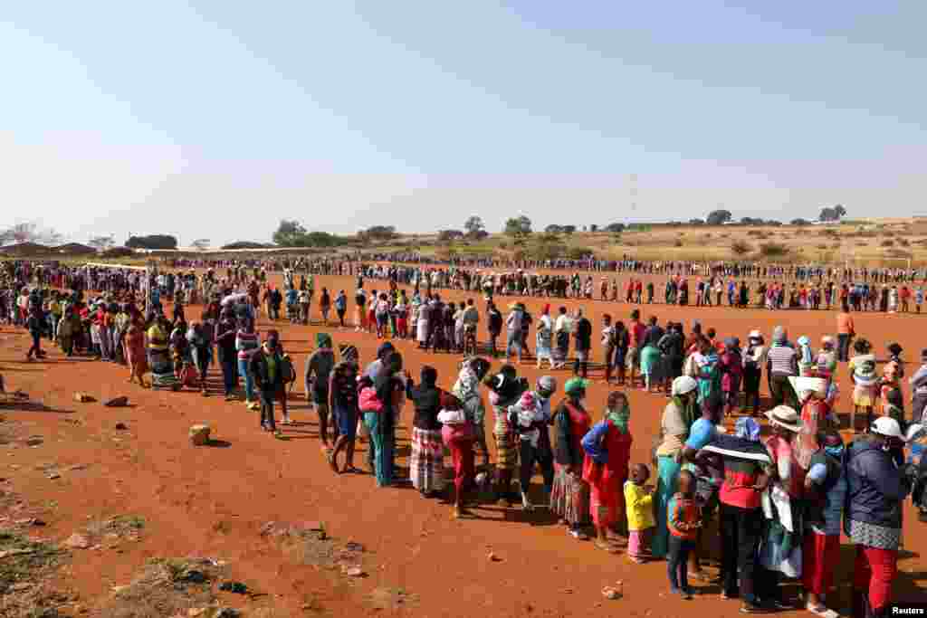 People stand in a line to receive food aid as the spread of the coronavirus disease (COVID-19) continues, at the Itireleng informal settlement, near Laudium suburb in Pretoria, South Africa.