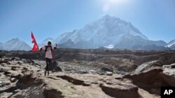 FILE - A Nepalese runs with his national flag during a marathon to mark the first conquest of Mount Everest, at Lobuche, near Everest base camp, Nepal, Monday, May 29, 2017. (AP Photo/Tashi Sherpa)