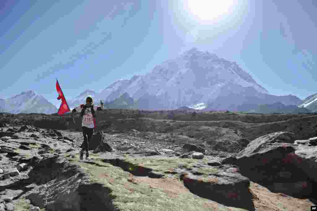 세계최고봉 에베레스트 첫 등정을 기념, 베이스캠프 인근에서 진행된 마라톤대회에서 국기들 든 네팔 출신 참가자가 달리고 있다. &nbsp;