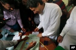 Pakistani politician Imran Khan, center, chief of Pakistan Tehreek-e-Insaf party, casts his vote at a polling station for the parliamentary elections in Islamabad, Pakistan, July 25, 2018.