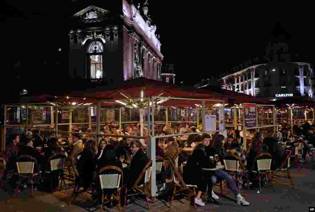 People enjoy a meal in Lille, northern France, Friday, Oct. 16, 2020. France is deploying 12,000 police officers to enforce a new curfew coming into effect Friday night for the next month to slow the virus spread, and will spend another 1 billion euros to