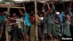 Rohingya refugees jostle as they line up for a blanket distribution under heavy rainfall at the Balukhali camp near Cox's Bazar, Bangladesh, Dec. 11, 2017.