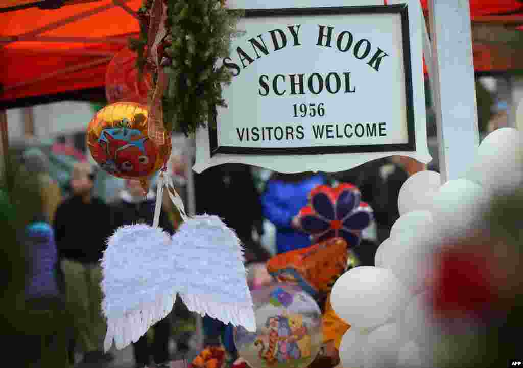 A pair of angel wings and balloons stand after being offered at a makeshift shrine to the victims of a elementary school shooting in Newtown, Connecticut, December 16, 2012.
