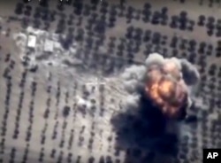 FILE - In this photo made from the footage taken from Russian Defense Ministry official web site on Friday, Oct. 16, 2015 showing a target hit during a Russian air raid in Syria. Russian Defense Ministry said the strike was performed by an Su-24M bomber in Idlib.