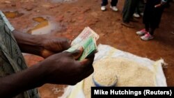 Un commerçant compte de l'argent reçu de la vente du maïs près de Lilongwe, la capitale du Malawi, le 1er février 2016. (Photo: REUTERS/Mike Hutchings)