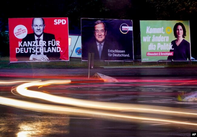 Three elections posters show Social Democratic top candidate for chancellor Olaf Scholz, L, Christian Democratic top candidate Armin Laschet, center, and top candidate of the Greens Annalena Baerbock, R, in Frankfurt, Germany, Sept. 15, 2021.