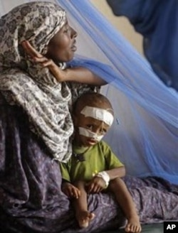A woman sits with her child at a local hospital to receive treatment for malnutrition at the border town of Dadaab, Kenya, Saturday, July 23, 2011