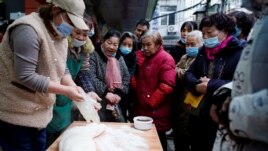 People wearing protective masks wait to buy food at a street market almost a year after the start of the coronavirus disease (COVID-19) outbreak, in Wuhan, Hubei province, China December 7, 2020. Picture taken December 7, 2020. REUTERS/Aly Song