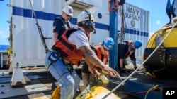 Contractors and Lt. Cmdr. Daniel Neverosky retrieve and secure the tow pinger locator aboard the USNS Apache, which left Norfolk, Va., on Oct. 19, to begin searching for wreckage from the missing cargo ship El Faro, Oct. 24, 2015.