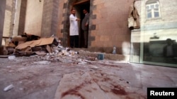 A doctor points at blood inside the hospital at the scene of the attack during a tour for journalists and survivors at the Defense Ministry in Sana'a Dec. 19, 2013.