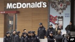 Police officers ask a journalist, lower right, to leave as he covers people gathering in front of a McDonald's restaurant which was a planned protest site in Beijing, February 20, 2011. Jittery Chinese authorities staged a concerted show of force Sunday t