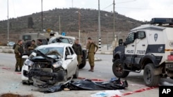 Tentara Israel dan polisi perbatasan berdiri dekat mayat seorang Palestina, tengah, yang menabrakkan mobilnya ke sekelompok orang Israel di Tepi Barat, dekat kota Palestina, Nablus, Minggu, 8 November 2015. Four Israelis were wounded from the incident and the attacker was shot dead by paramilitary officers, Israeli police said. (AP Photo/Ariel Schalit)